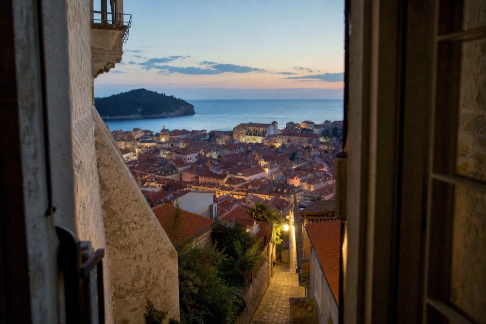 An evening view over Dubrovnik rooftops with the illuminated Old Town below