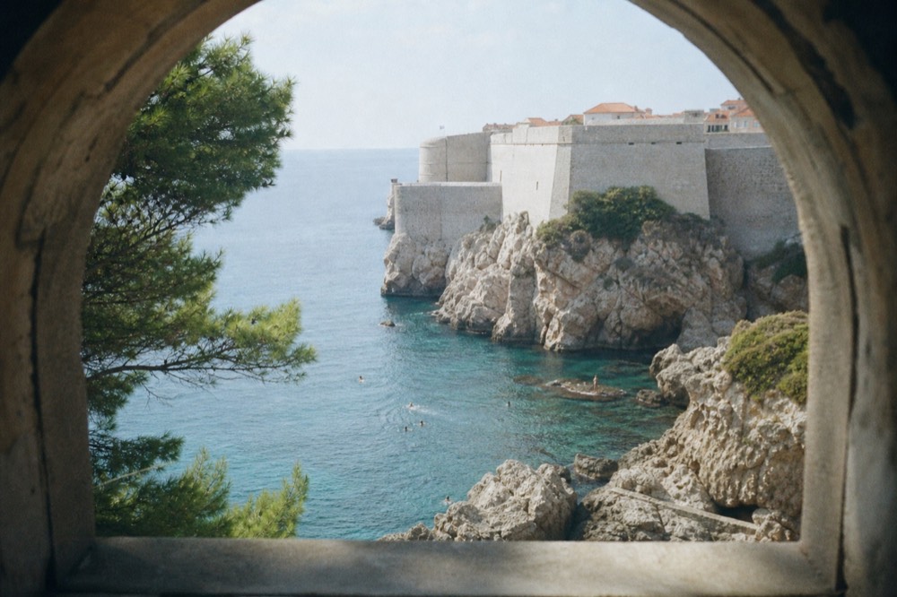Swimmers in clear blue Adriatic water below Dubrovnik's walls
