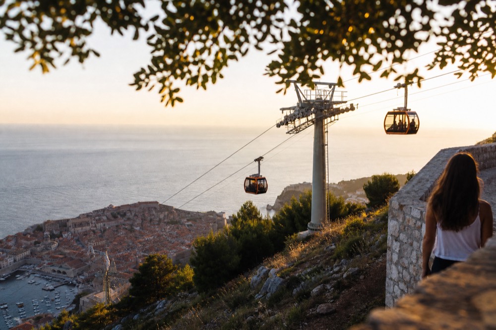 Cable car cabins ascending the hill above Dubrovnik Old Town at golden hour