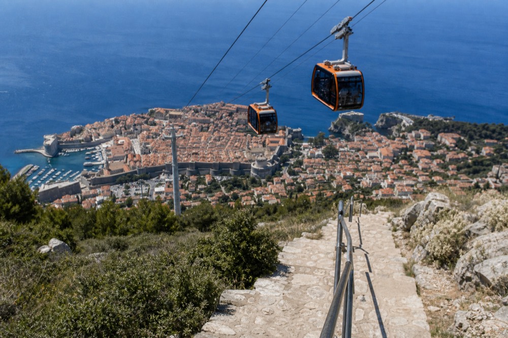 Cable car cabins travelling up the hillside above Dubrovnik's red rooftops