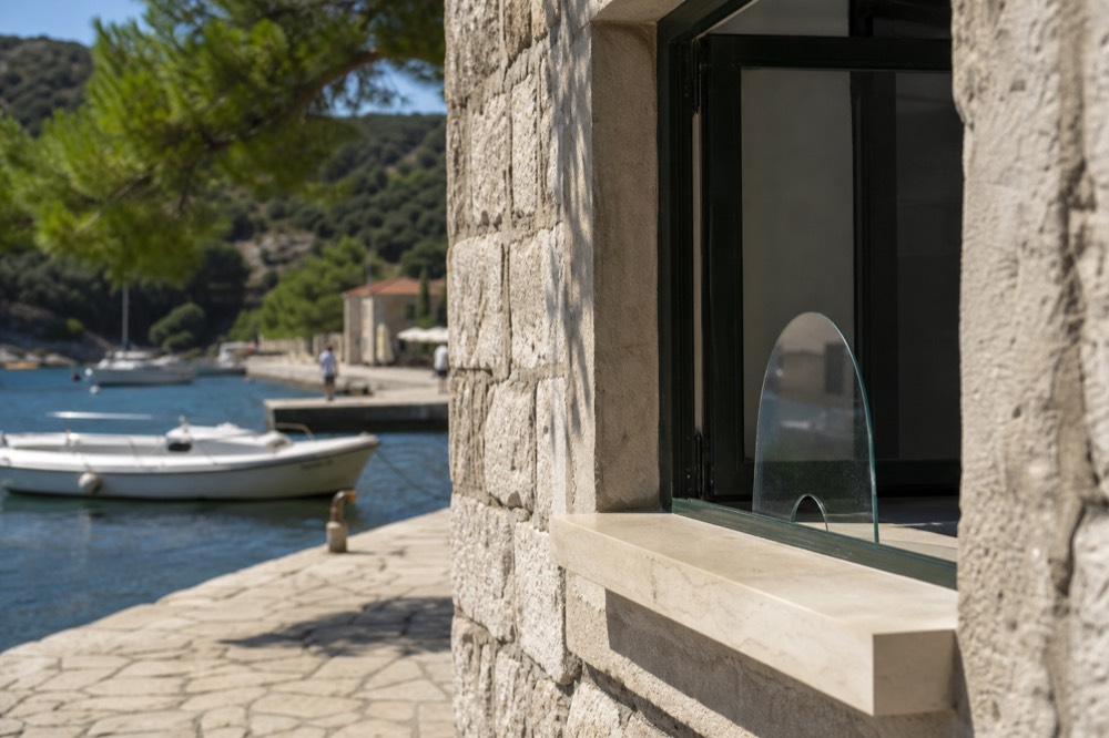 A ticket office window beside a stone harbour with moored boats