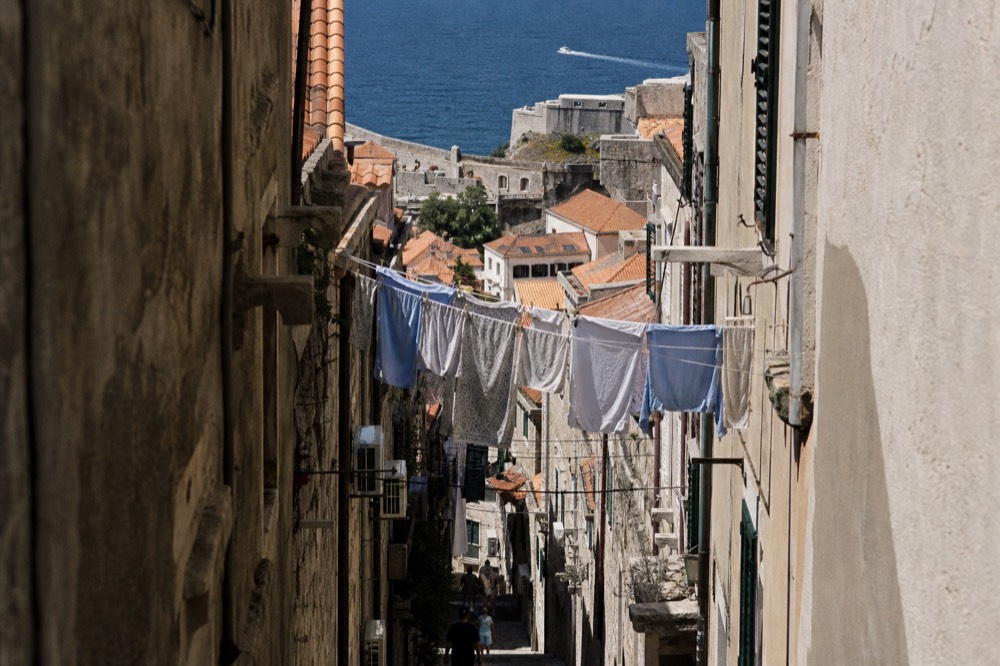 Narrow stone lane in Dubrovnik Old Town with laundry hanging between aged buildings