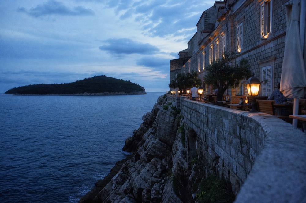 Seafront hotel terrace above a rocky Adriatic shoreline at dusk