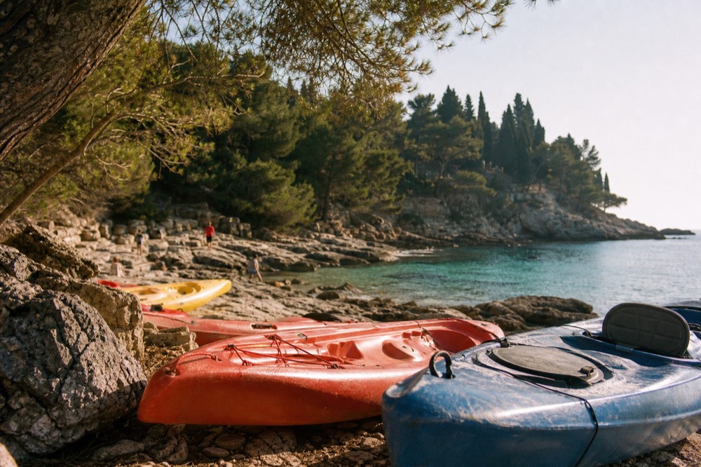 Kayaks resting on a rocky beach beside clear turquoise water near Dubrovnik