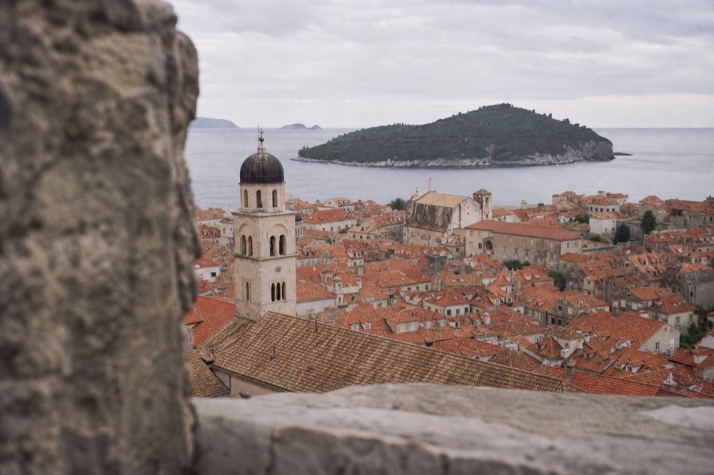 Red rooftops and bell towers of Dubrovnik Old Town seen from a high stone wall