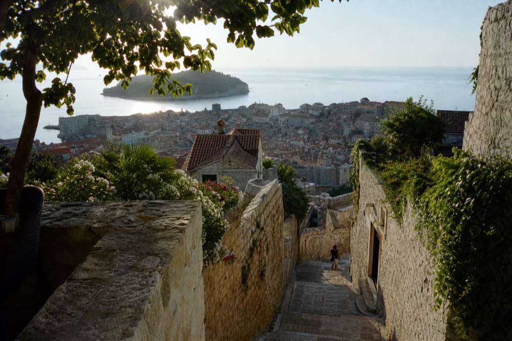 A panoramic view over a walled coastal city with islands on the horizon