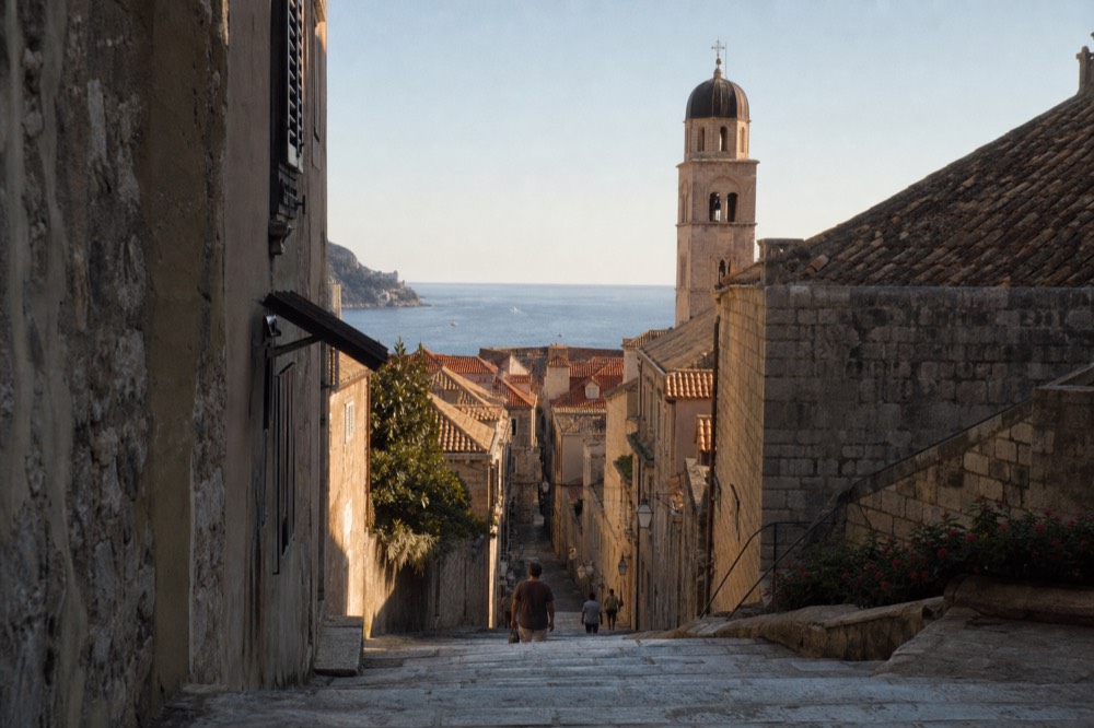 Stone steps in Dubrovnik framed by old buildings with a church tower above