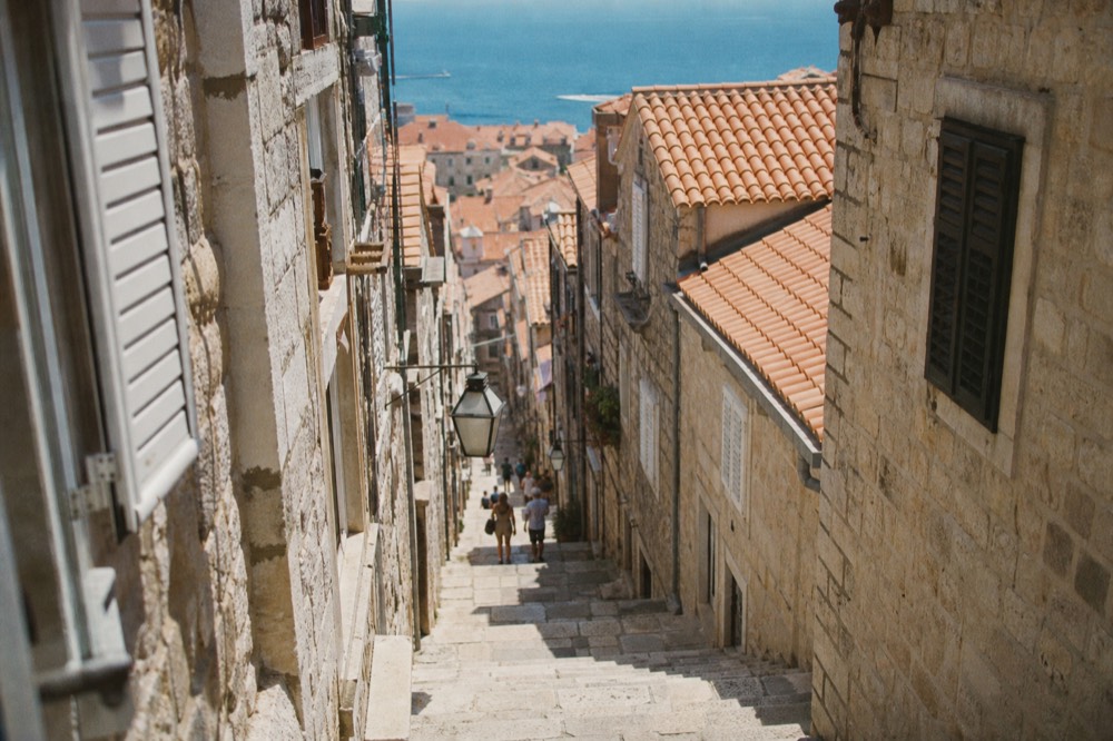 A sunny lane with stone buildings leading uphill in Dubrovnik Old Town