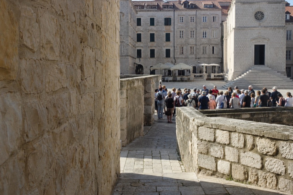 Guides and visitors gathered at an stone square in Dubrovnik Old Town