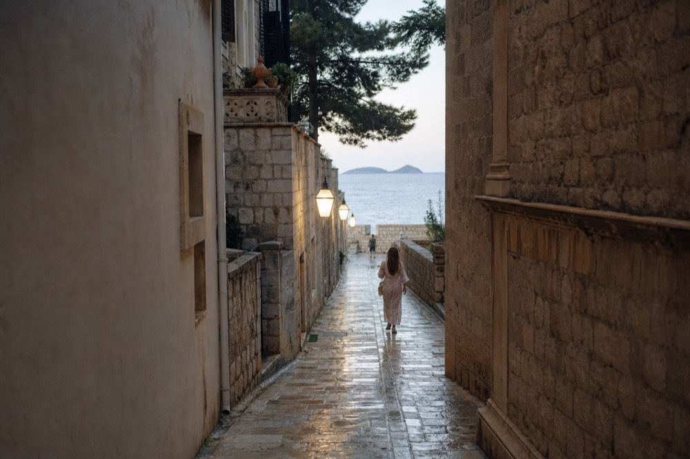 Wet limestone paving of a narrow Dubrovnik alley reflecting street lights after rain
