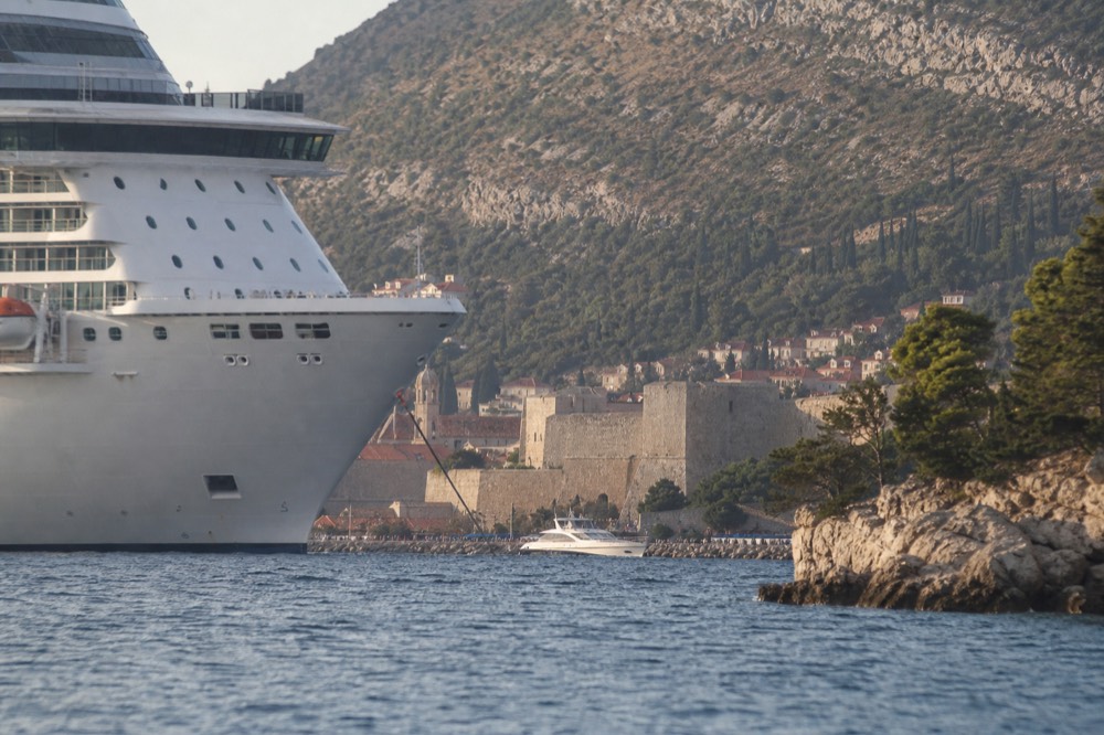 A large cruise ship moored near the walled city of Dubrovnik seen from the water