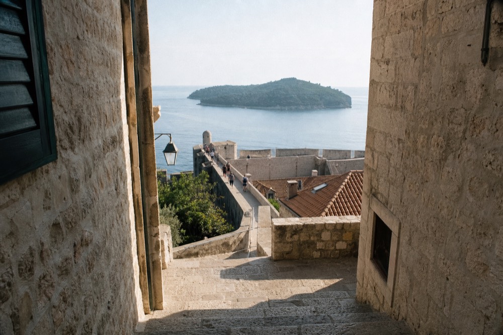 Walkers on the city walls of Dubrovnik with the Adriatic sea and Lokrum island in the distance