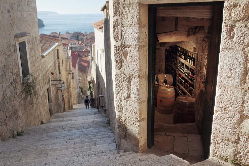 A stone wine cellar with oak barrels and bottles racked along the wall