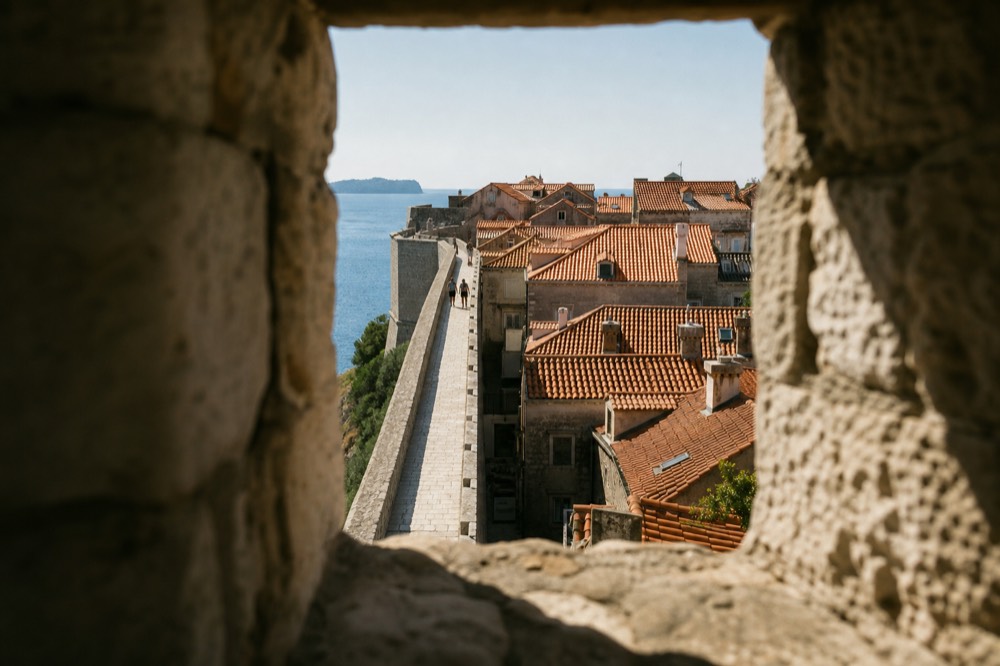 Stone walkway along the top of Dubrovnik city walls with the terracotta Old Town rooftops below