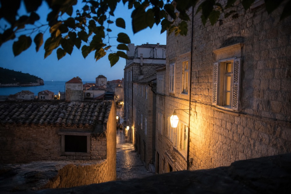 A quiet stone street inside Dubrovnik Old Town at dusk with warm light on the walls