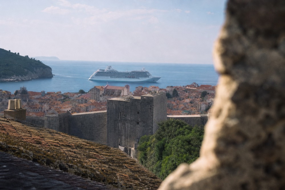 A cruise ship anchored off the walled city of Dubrovnik in morning light
