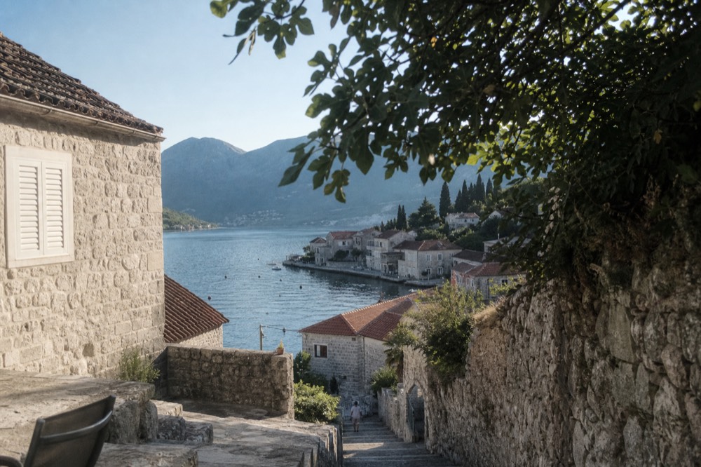 View of the Bay of Kotor with stone buildings at the water's edge and steep mountains behind