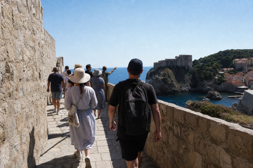 A guided walking group on the city walls with a local guide pointing out a landmark against the sea