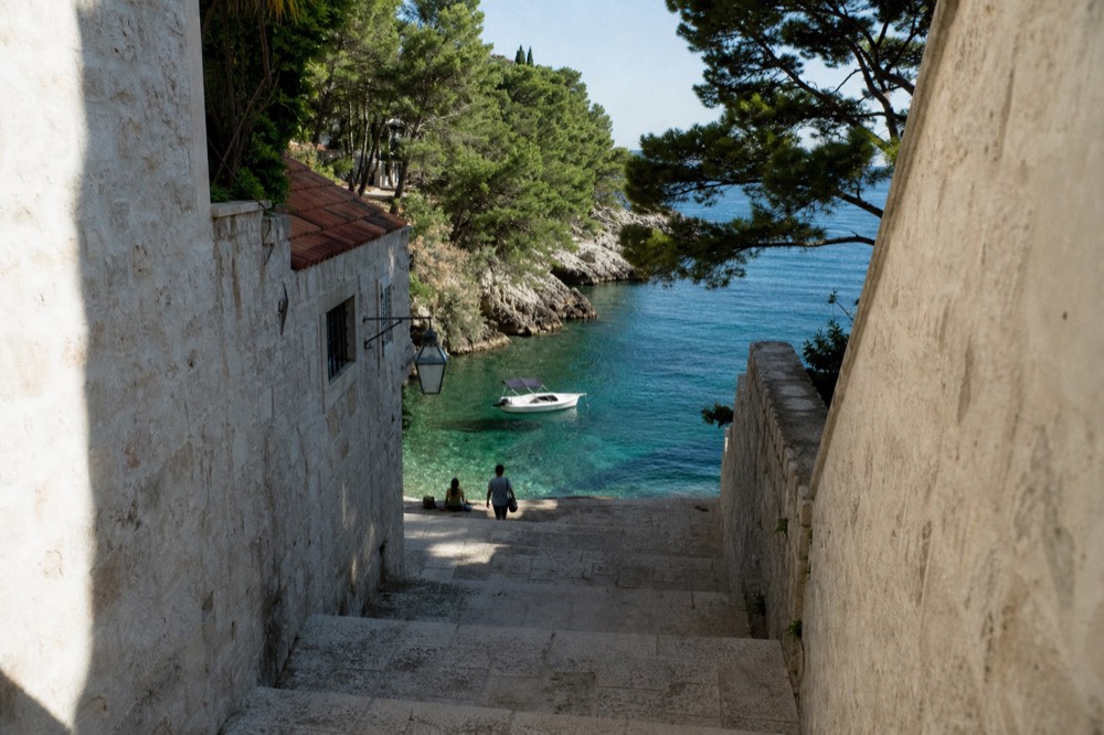 A small self-drive boat anchored in a quiet cove with turquoise water and pine-covered shoreline