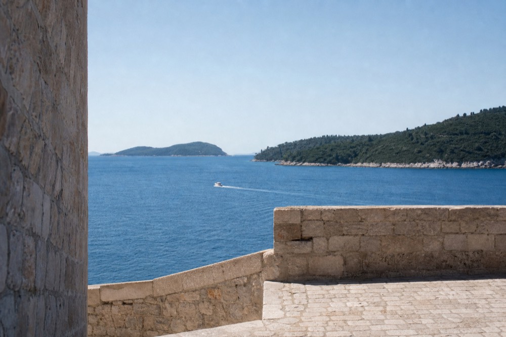A small boat crossing open blue water toward green islands on the horizon